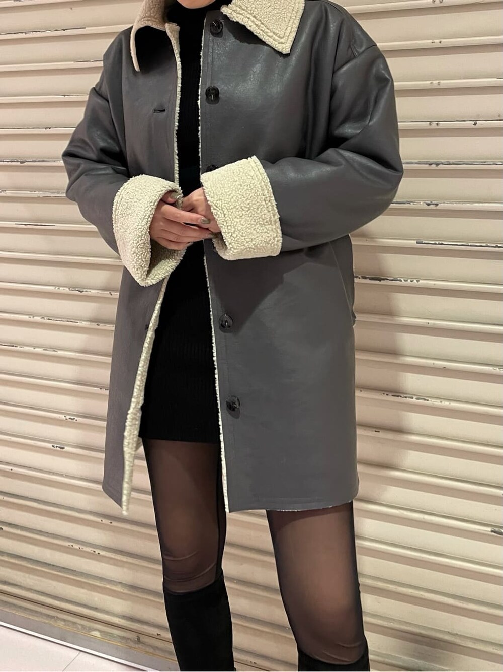 グレー系のムートンコート、ブラック系のブーツを着用したレディースの冬コーディネートの6枚目の写真