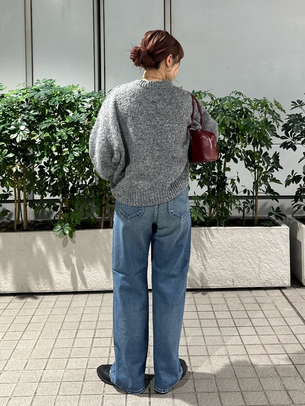 グレー系のニット/セーター、ブルー系のデニムパンツ、レッド系のハンドバッグを着用したレディースの秋コーディネートの4枚目の写真