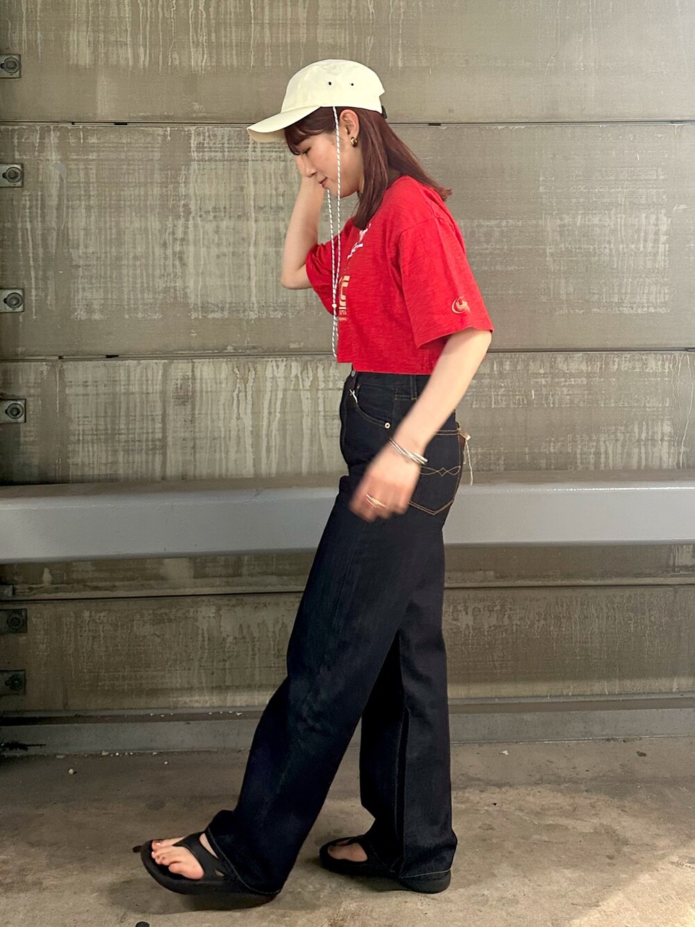 レッド系のTシャツ/カットソー、ブルー系のデニムパンツ、ホワイト系のキャップを着用したレディースの春コーディネートの4枚目の写真