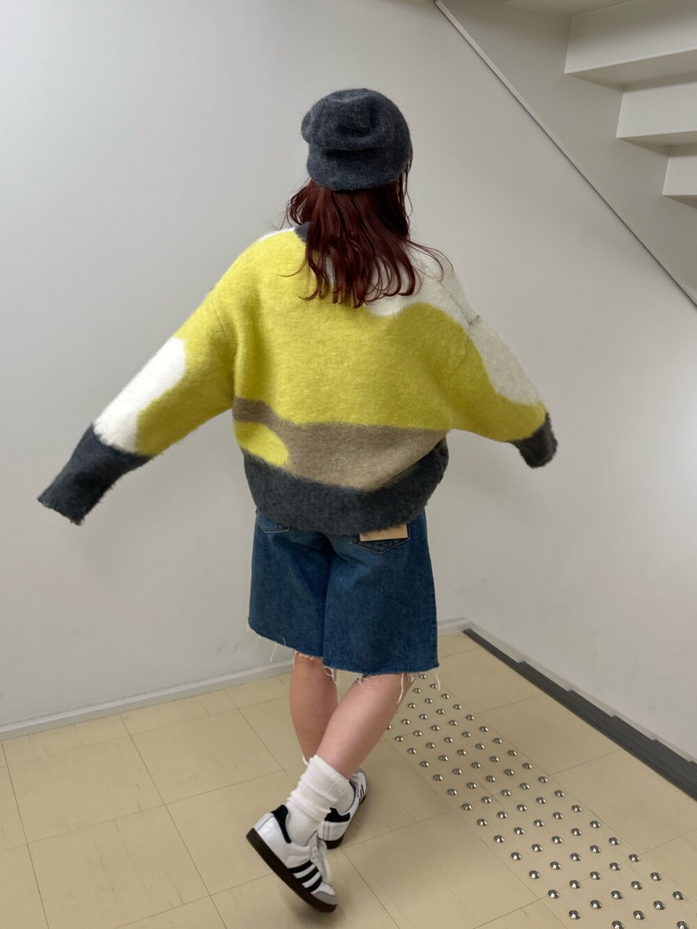 グリーン系のニット/セーター、ブルー系のデニムパンツを着用したレディースの秋コーディネートの4枚目の写真