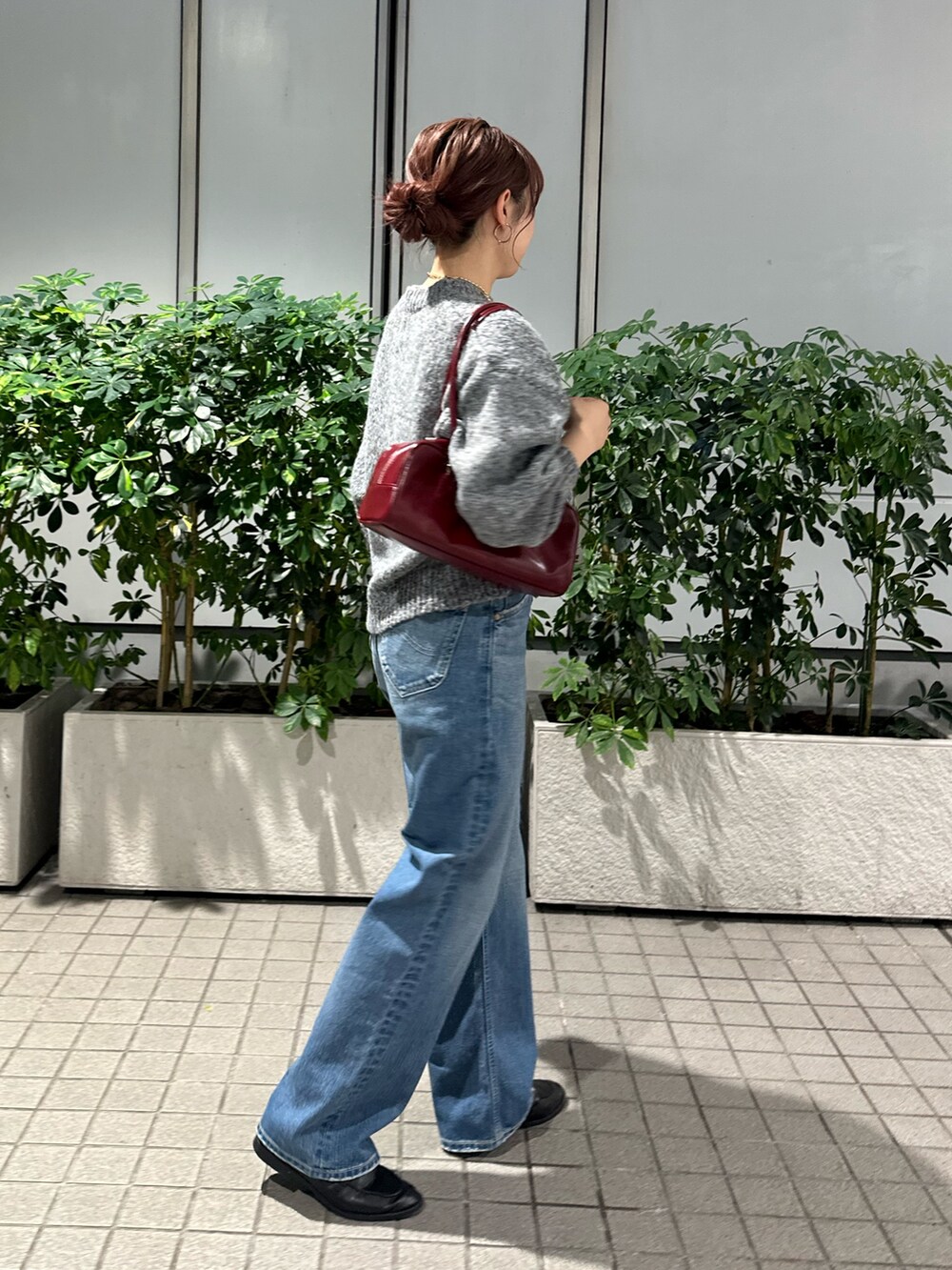 グレー系のニット/セーター、ブルー系のデニムパンツ、レッド系のハンドバッグを着用したレディースの秋コーディネートの3枚目の写真