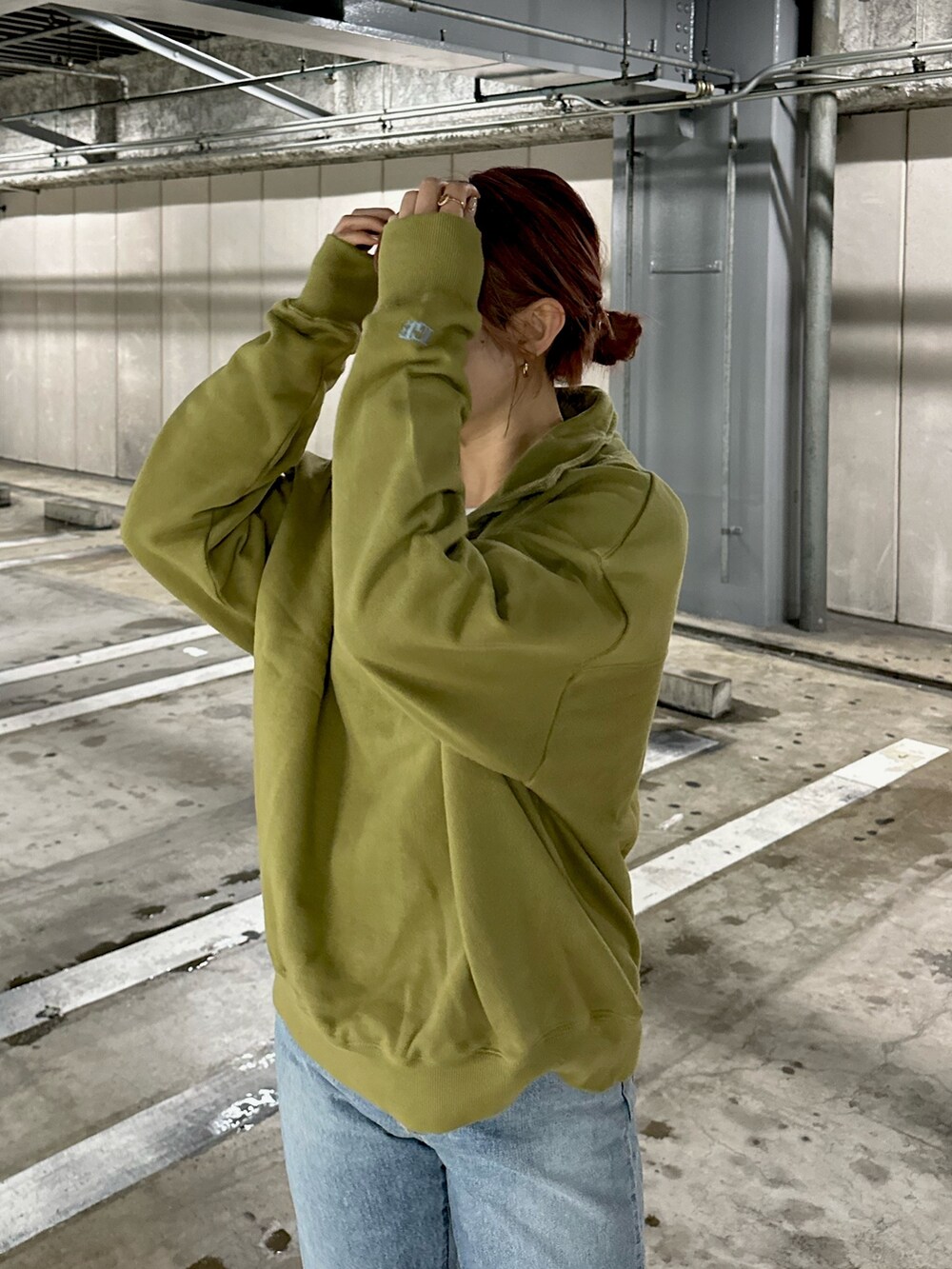 グリーン系のスウェット、ブルー系のデニムパンツを着用したレディースの冬コーディネートの3枚目の写真