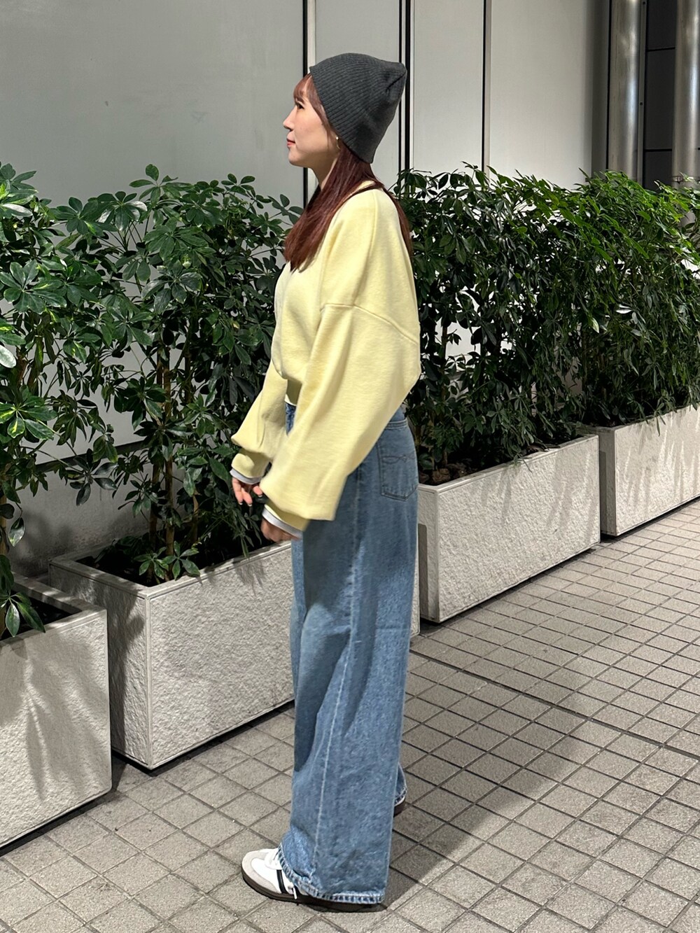 イエロー系のニット/セーター、ブルー系のデニムパンツ、グレー系のニットキャップ/ビーニーを着用したレディースの冬コーディネートの4枚目の写真