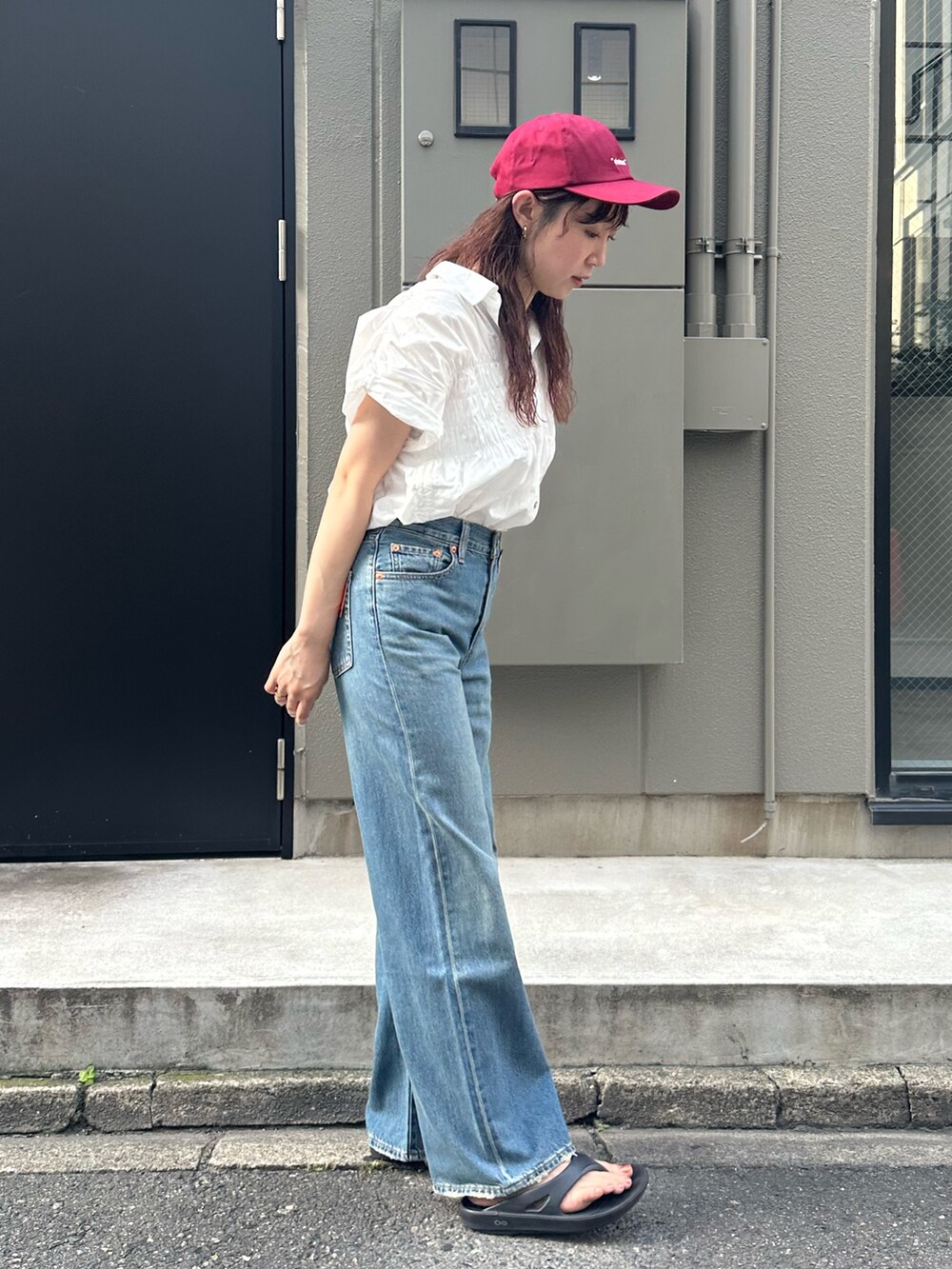 ブルー系のデニムパンツ、レッド系のキャップを着用したレディースの夏コーディネートの3枚目の写真