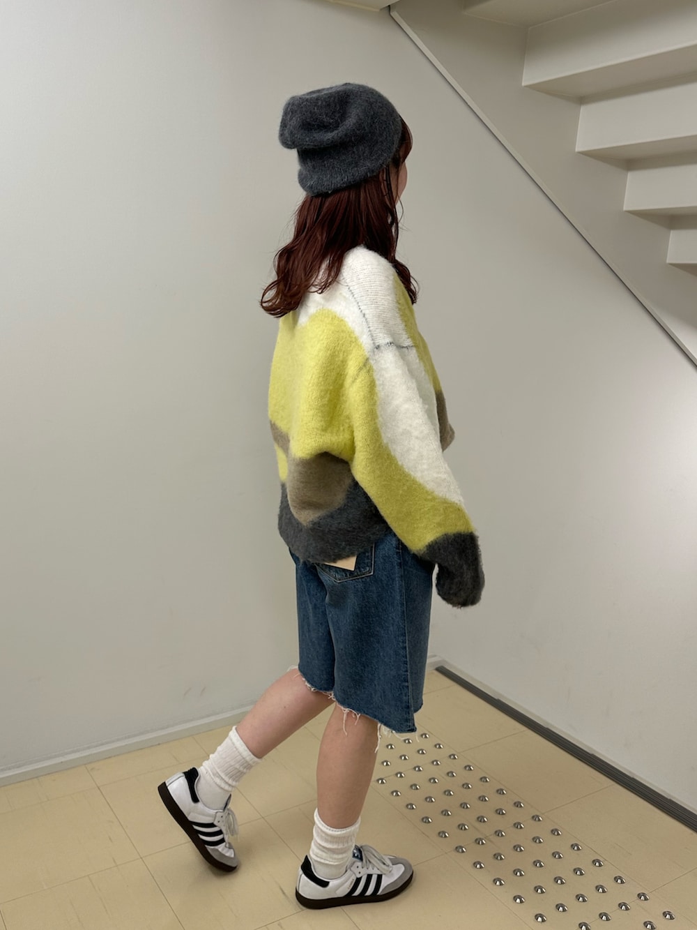 グリーン系のニット/セーター、ブルー系のデニムパンツを着用したレディースの秋コーディネートの2枚目の写真