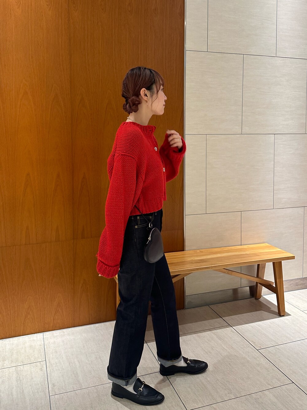 レッド系のカーディガン/ボレロ、ブルー系のデニムパンツ、ブラック系のショルダーバッグを着用したレディースの秋コーディネートの3枚目の写真