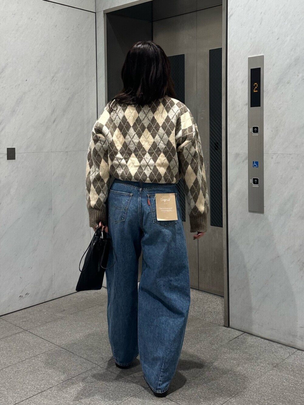 ベージュ系のニット/セーター、ブルー系のデニムパンツを着用したレディースの秋コーディネートの5枚目の写真