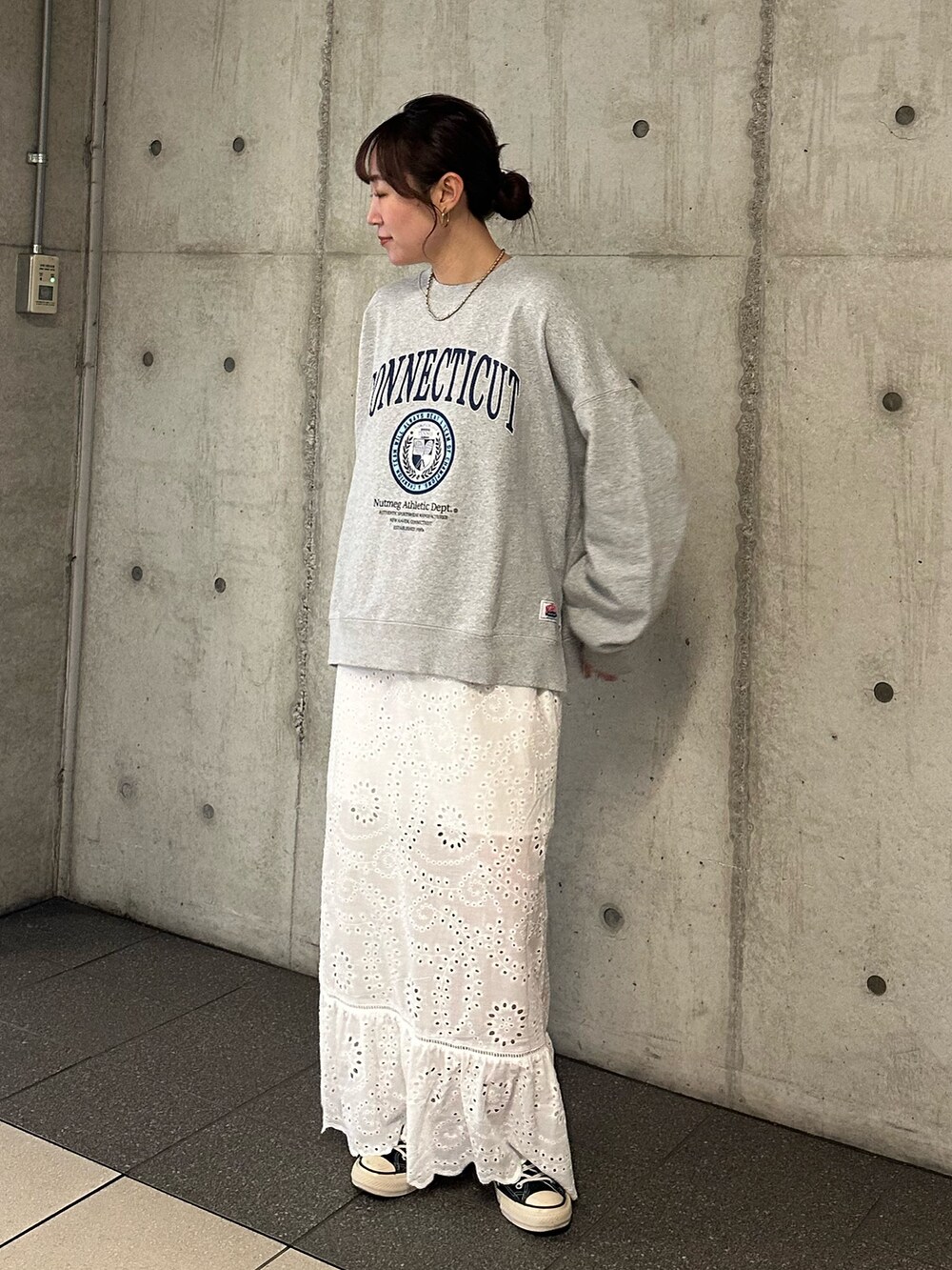 グレー系のスウェット、ホワイト系のスカートを着用したレディースの冬コーディネートの2枚目の写真