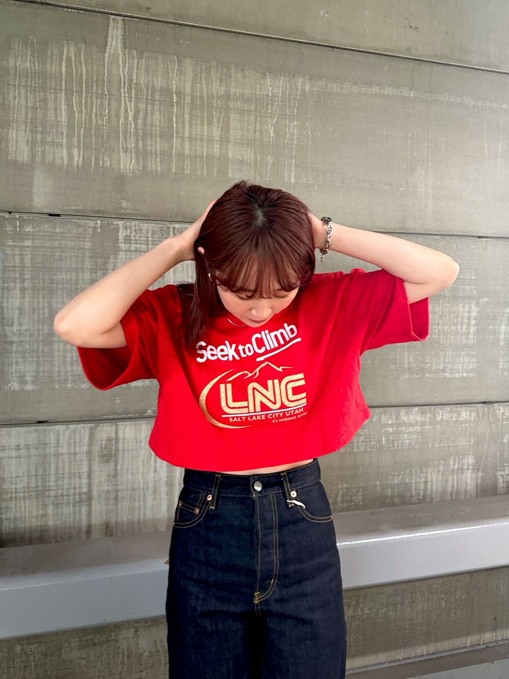 レッド系のTシャツ/カットソー、ブルー系のデニムパンツ、ホワイト系のキャップを着用したレディースの春コーディネートの7枚目の写真