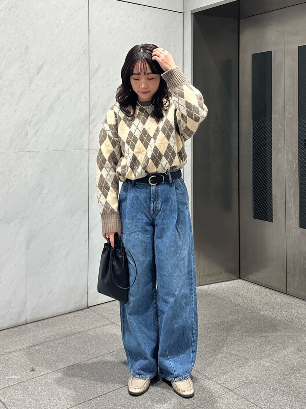 ベージュ系のニット/セーター、ブルー系のデニムパンツを着用したレディースの秋コーディネートの2枚目の写真