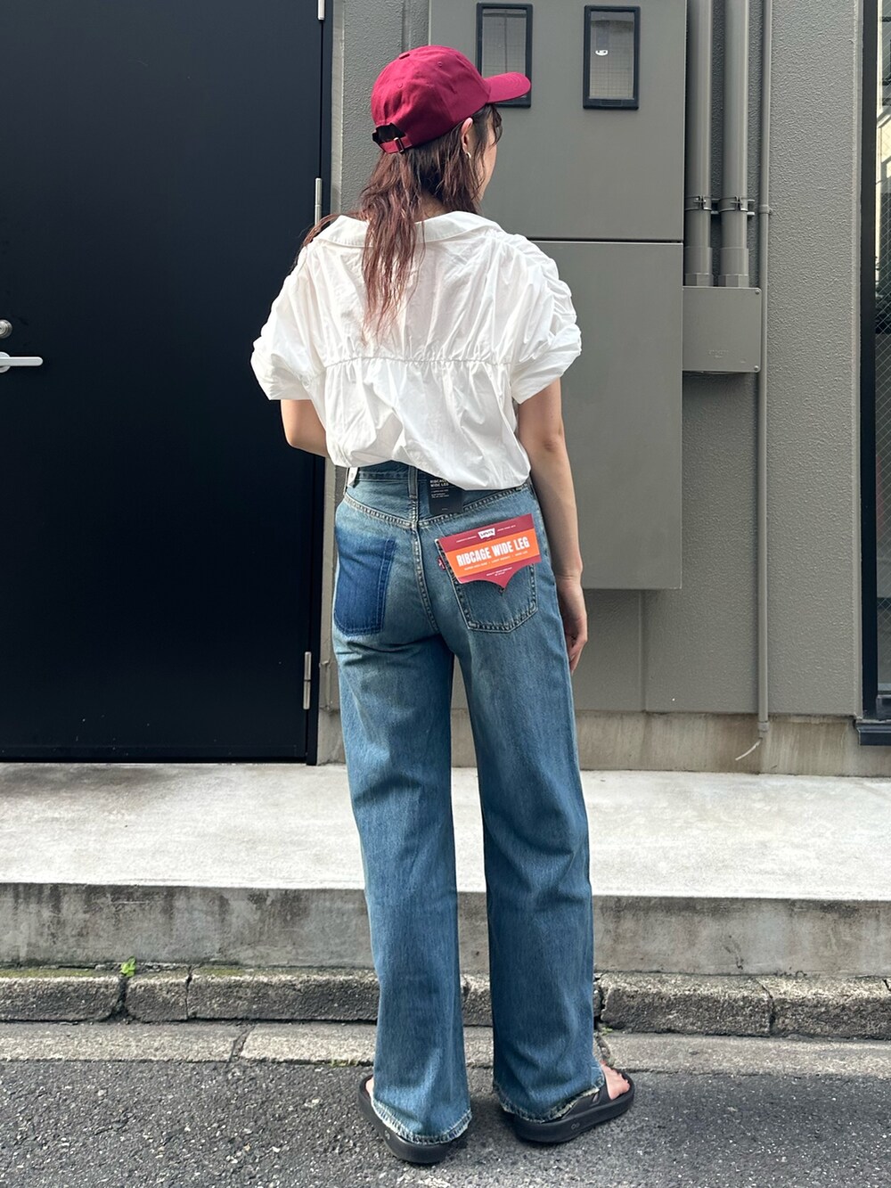 ブルー系のデニムパンツ、レッド系のキャップを着用したレディースの夏コーディネートの5枚目の写真