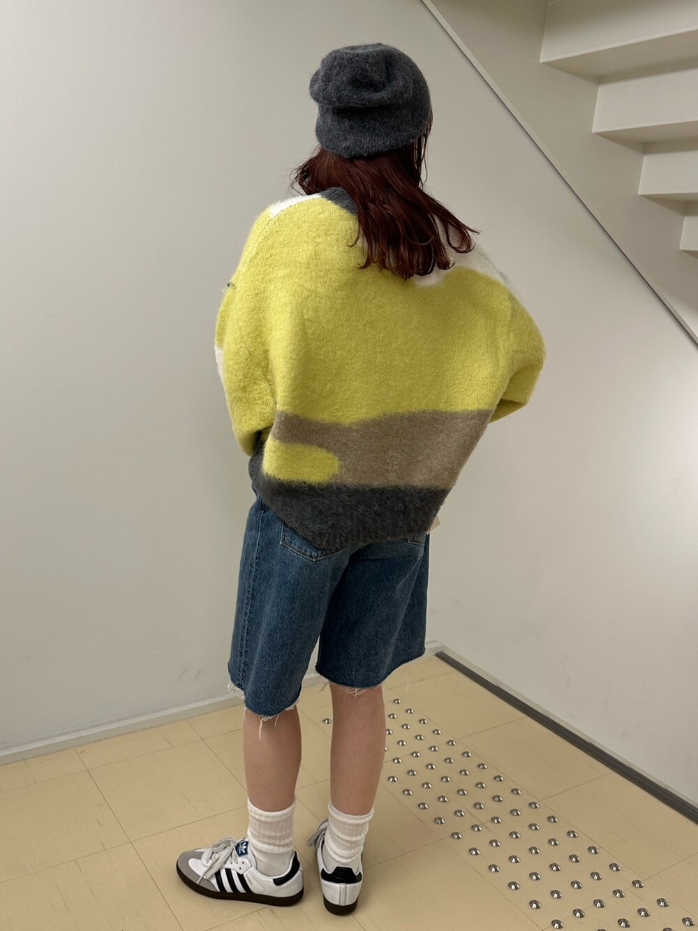 グリーン系のニット/セーター、ブルー系のデニムパンツを着用したレディースの秋コーディネートの3枚目の写真