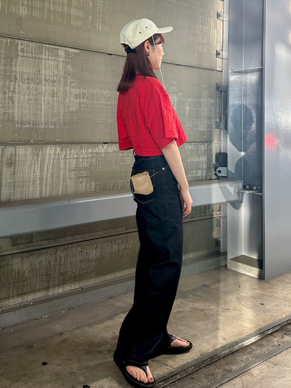 レッド系のTシャツ/カットソー、ブルー系のデニムパンツ、ホワイト系のキャップを着用したレディースの春コーディネートの3枚目の写真