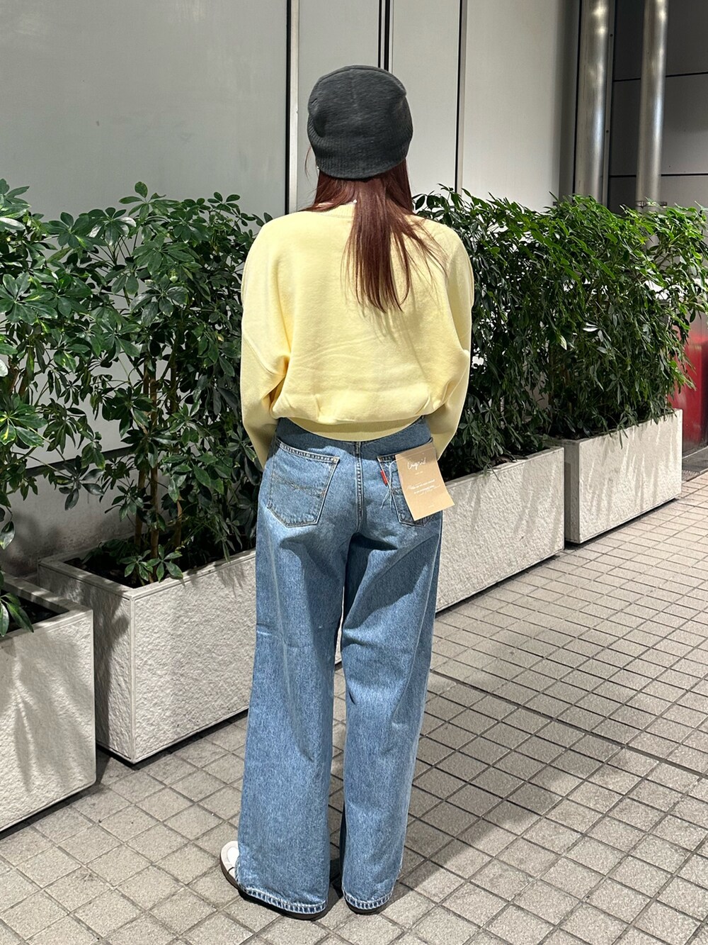 イエロー系のニット/セーター、ブルー系のデニムパンツ、グレー系のニットキャップ/ビーニーを着用したレディースの冬コーディネートの5枚目の写真