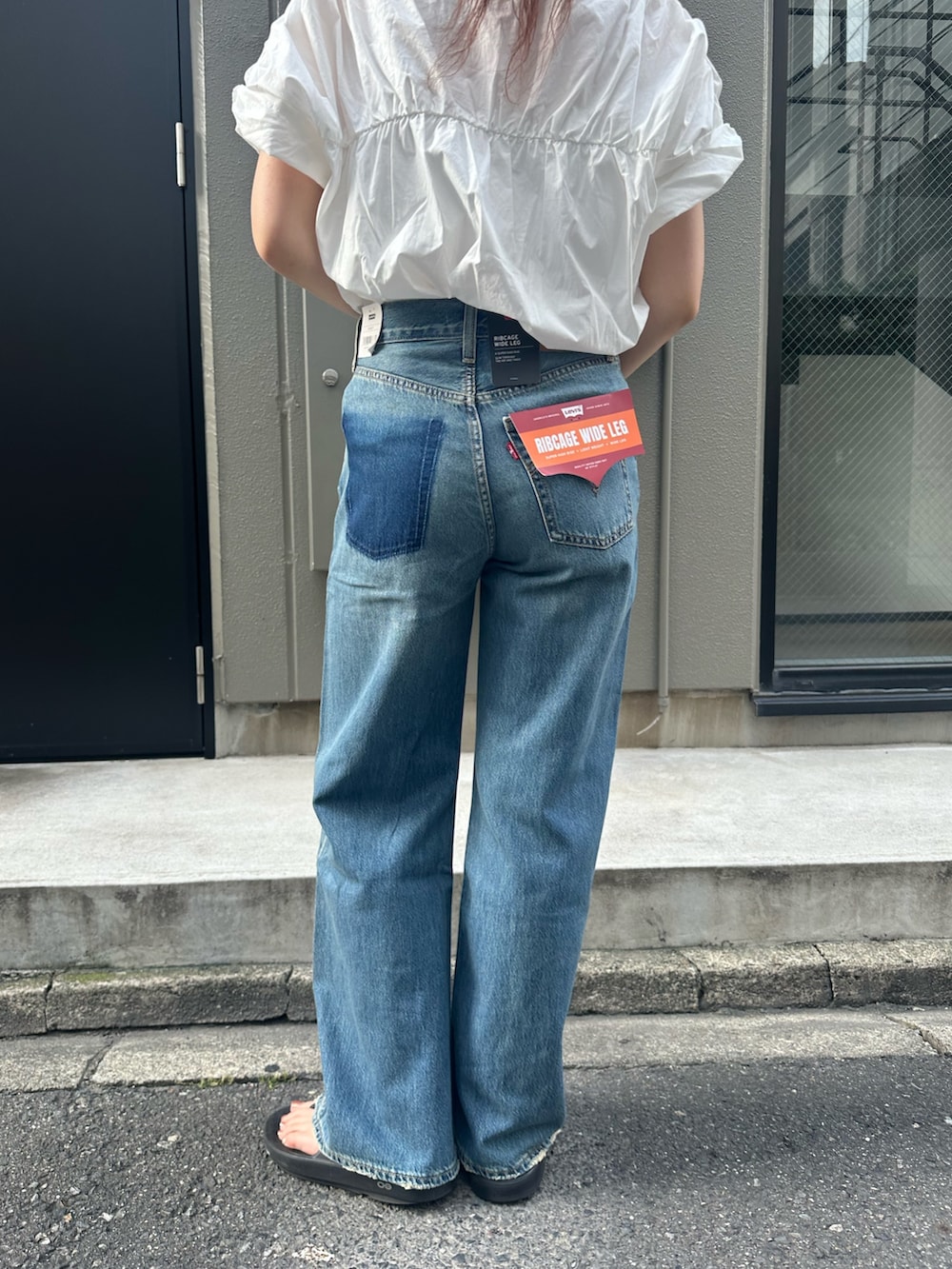 ブルー系のデニムパンツ、レッド系のキャップを着用したレディースの夏コーディネートの6枚目の写真