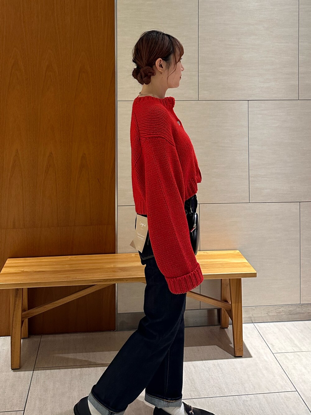 レッド系のカーディガン/ボレロ、ブルー系のデニムパンツ、ブラック系のショルダーバッグを着用したレディースの秋コーディネートの5枚目の写真