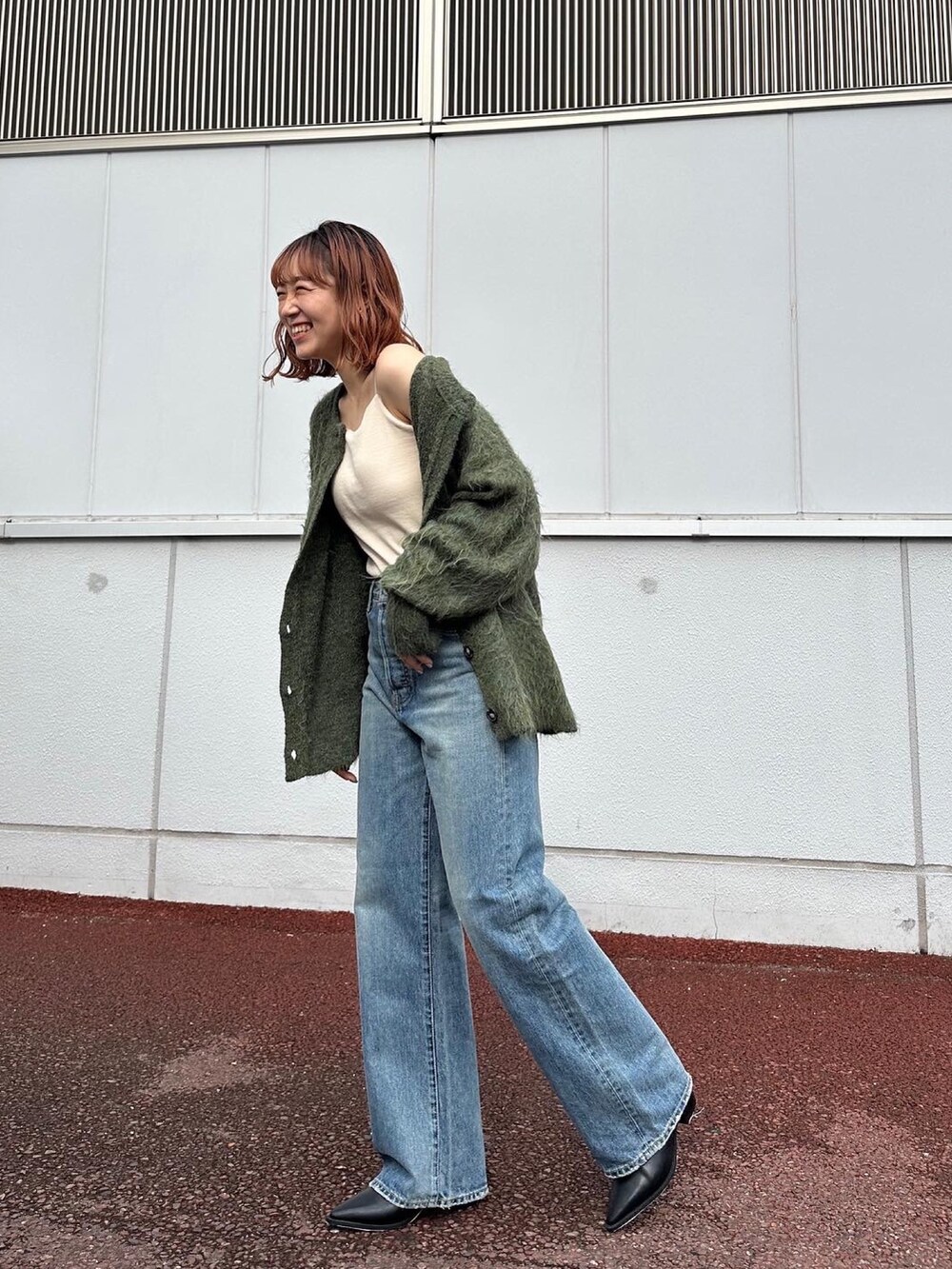 グリーン系のカーディガン/ボレロ、ブルー系のデニムパンツ、ブラック系のブーツを着用したレディースの秋コーディネートの2枚目の写真