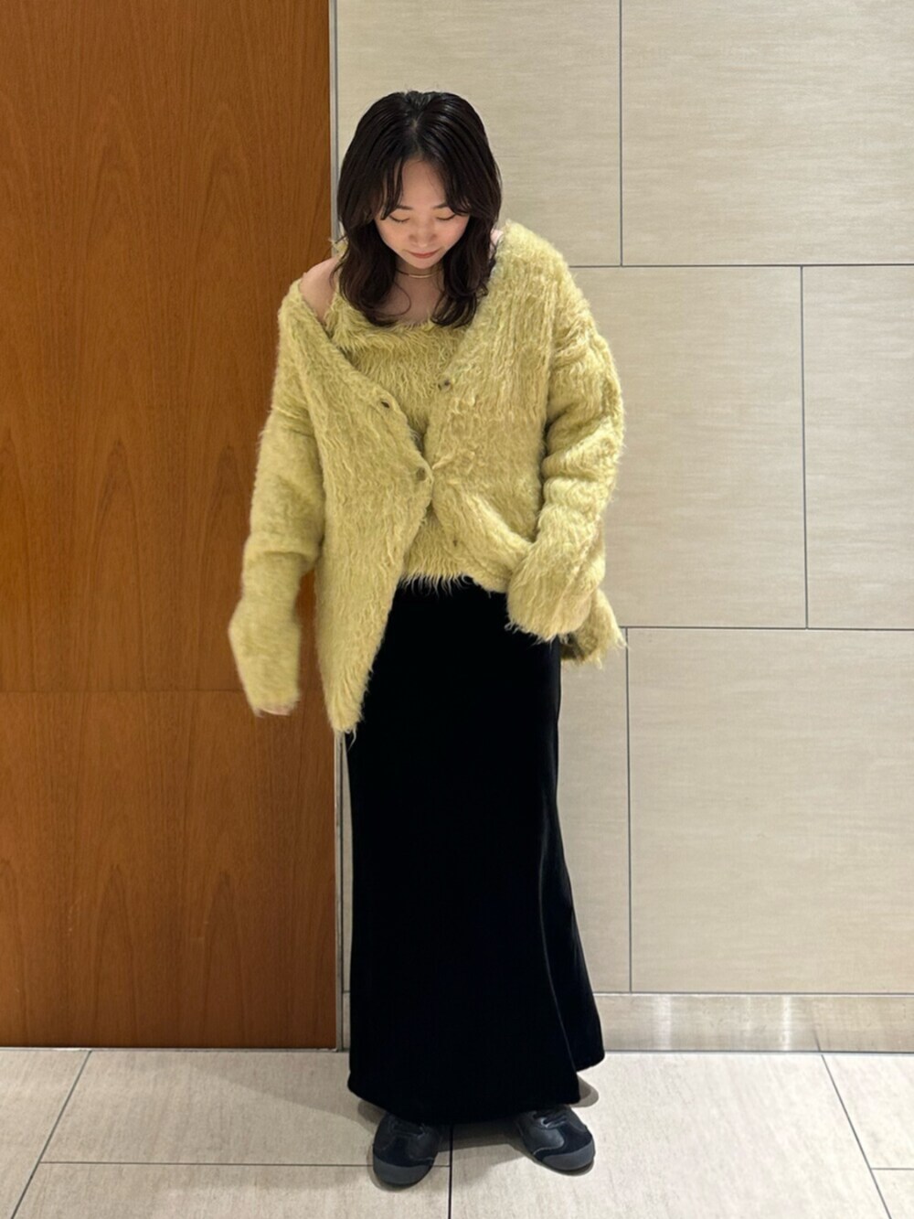 ブラック系のスカート、イエロー系のカーディガン/ボレロを着用したレディースの秋コーディネートの2枚目の写真