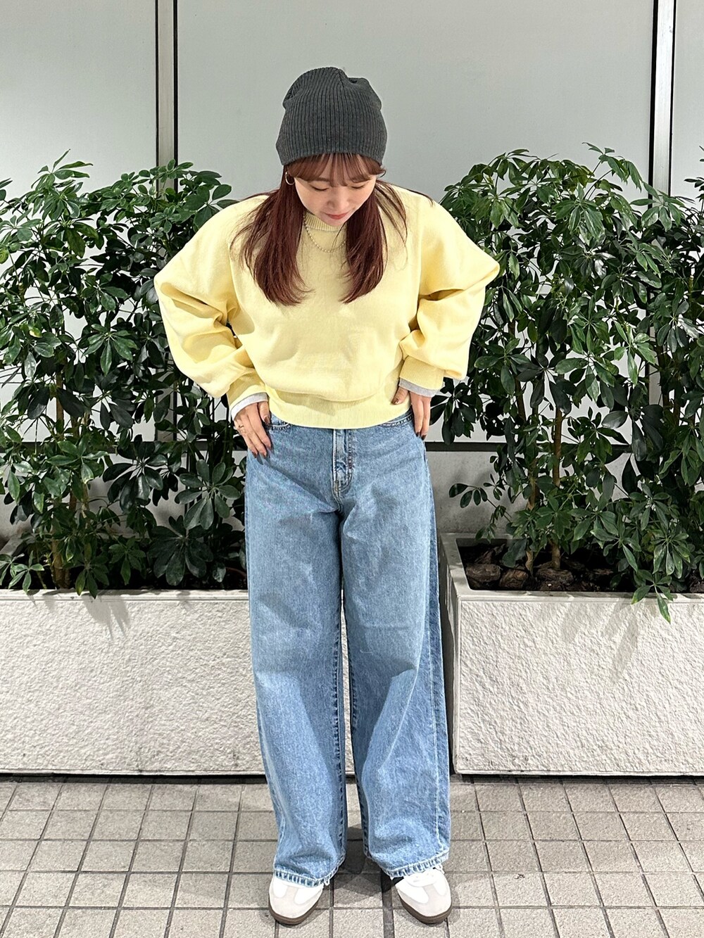 イエロー系のニット/セーター、ブルー系のデニムパンツ、グレー系のニットキャップ/ビーニーを着用したレディースの冬コーディネートの2枚目の写真