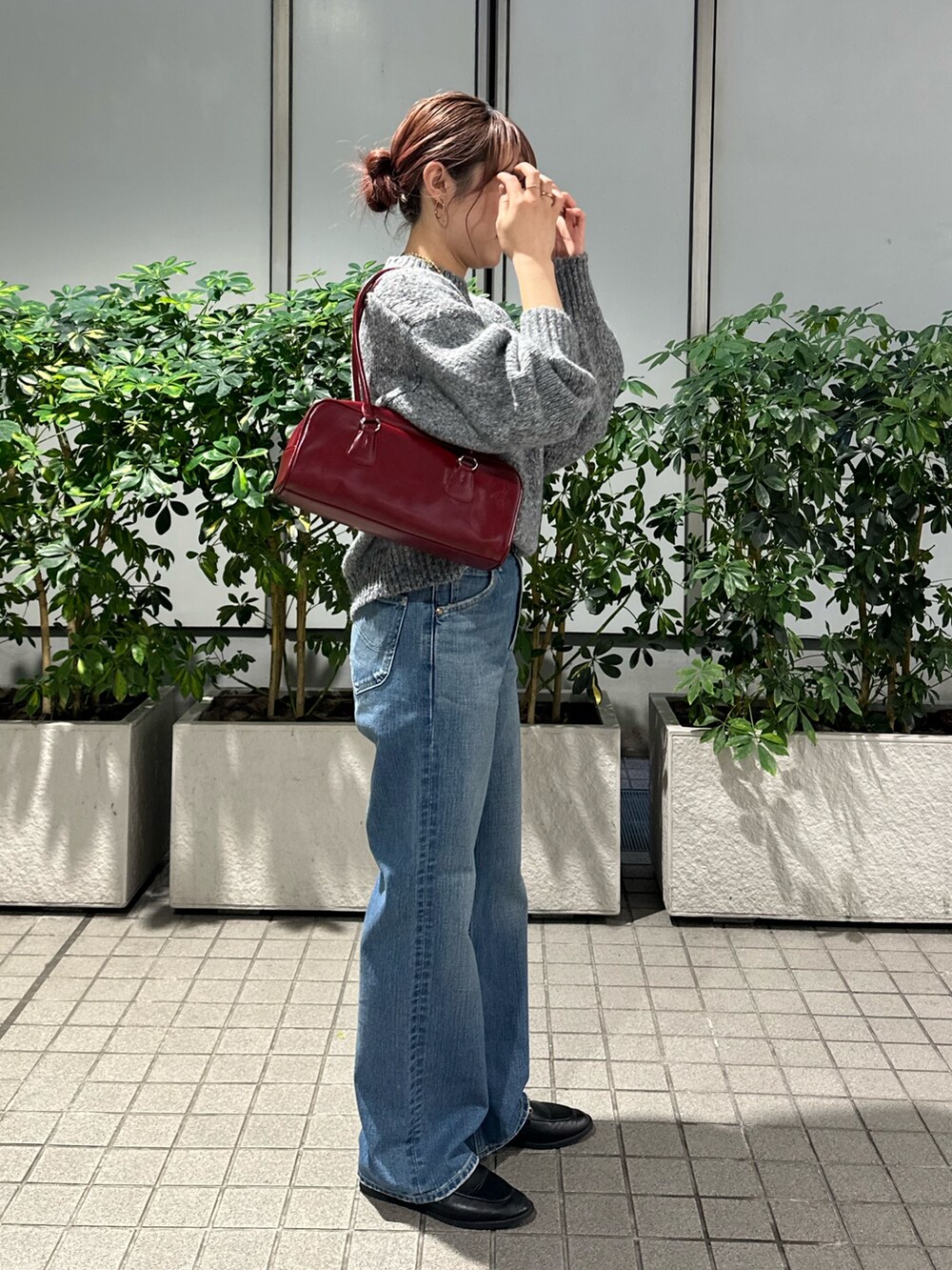グレー系のニット/セーター、ブルー系のデニムパンツ、レッド系のハンドバッグを着用したレディースの秋コーディネートの2枚目の写真