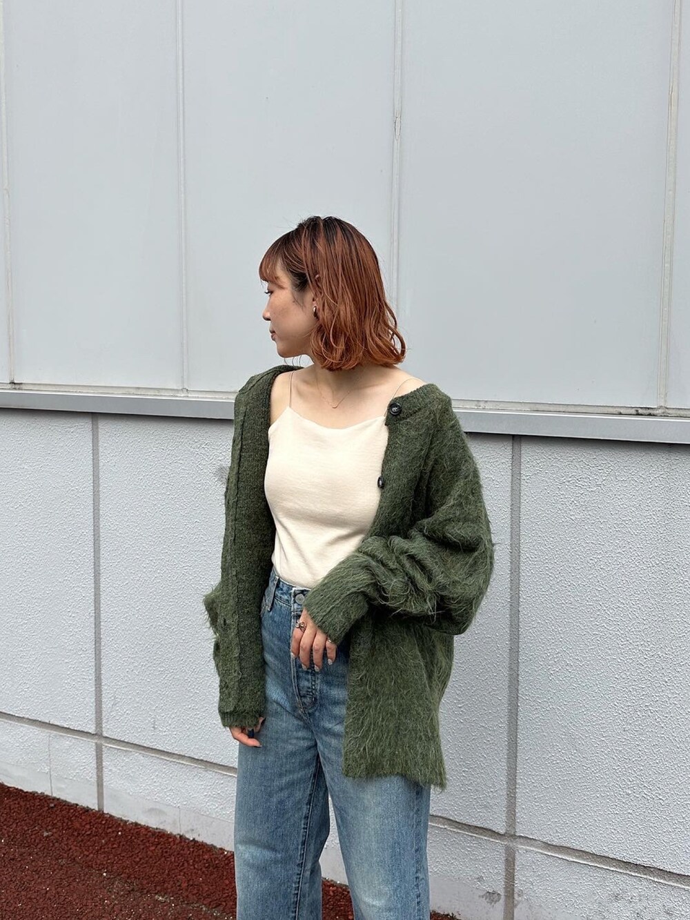 グリーン系のカーディガン/ボレロ、ブルー系のデニムパンツ、ブラック系のブーツを着用したレディースの秋コーディネートの3枚目の写真