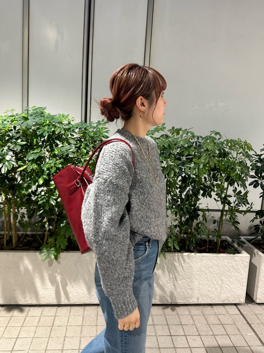 グレー系のニット/セーター、ブルー系のデニムパンツ、レッド系のハンドバッグを着用したレディースの秋コーディネートの6枚目の写真