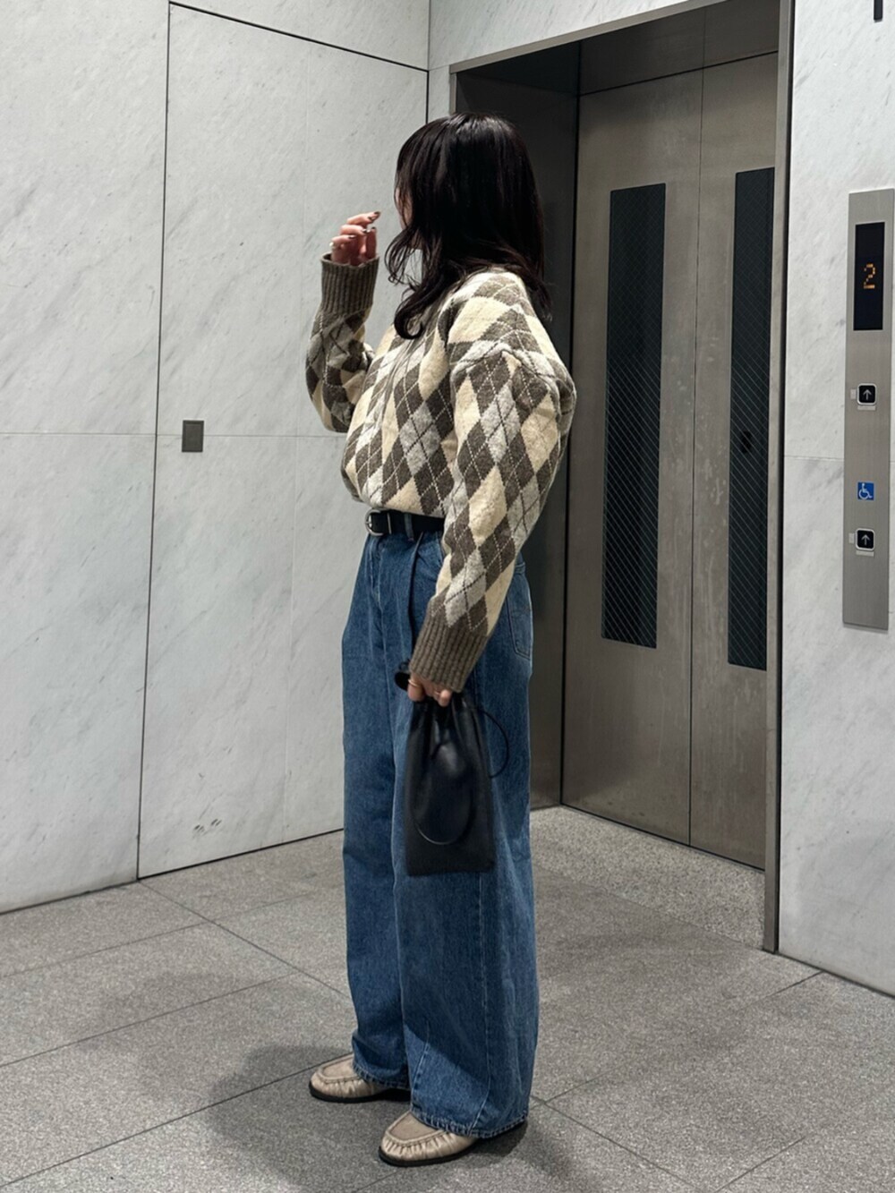 ベージュ系のニット/セーター、ブルー系のデニムパンツを着用したレディースの秋コーディネートの4枚目の写真