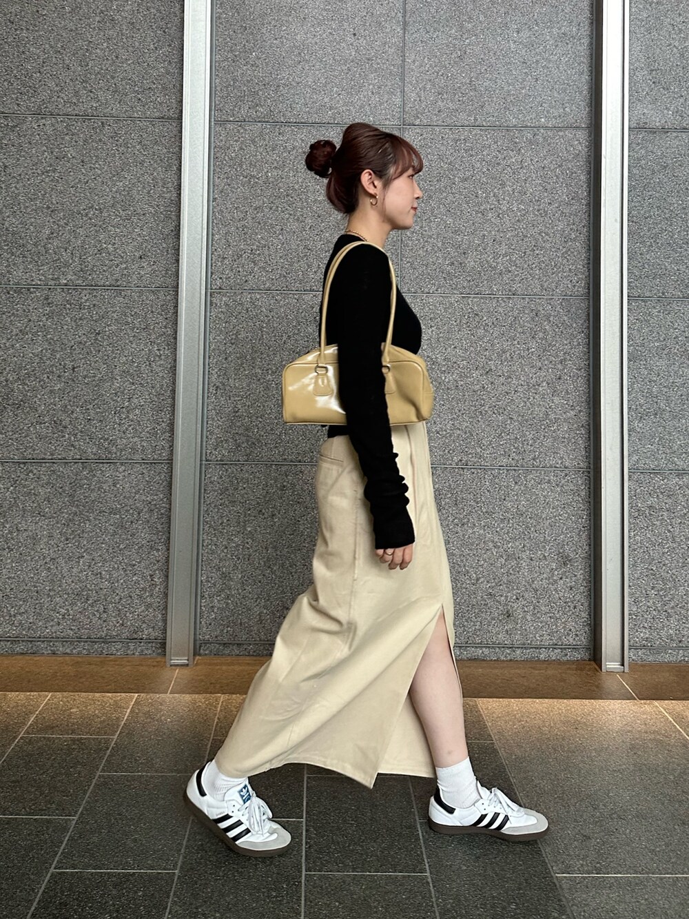 ブラック系のニット/セーター、ベージュ系のスカート、ベージュ系のハンドバッグを着用したレディースの秋コーディネートの3枚目の写真