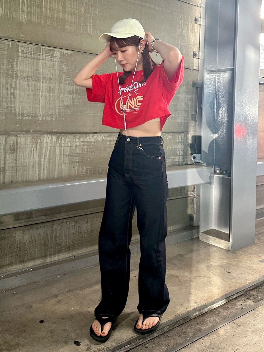 レッド系のTシャツ/カットソー、ブルー系のデニムパンツ、ホワイト系のキャップを着用したレディースの春コーディネートの2枚目の写真