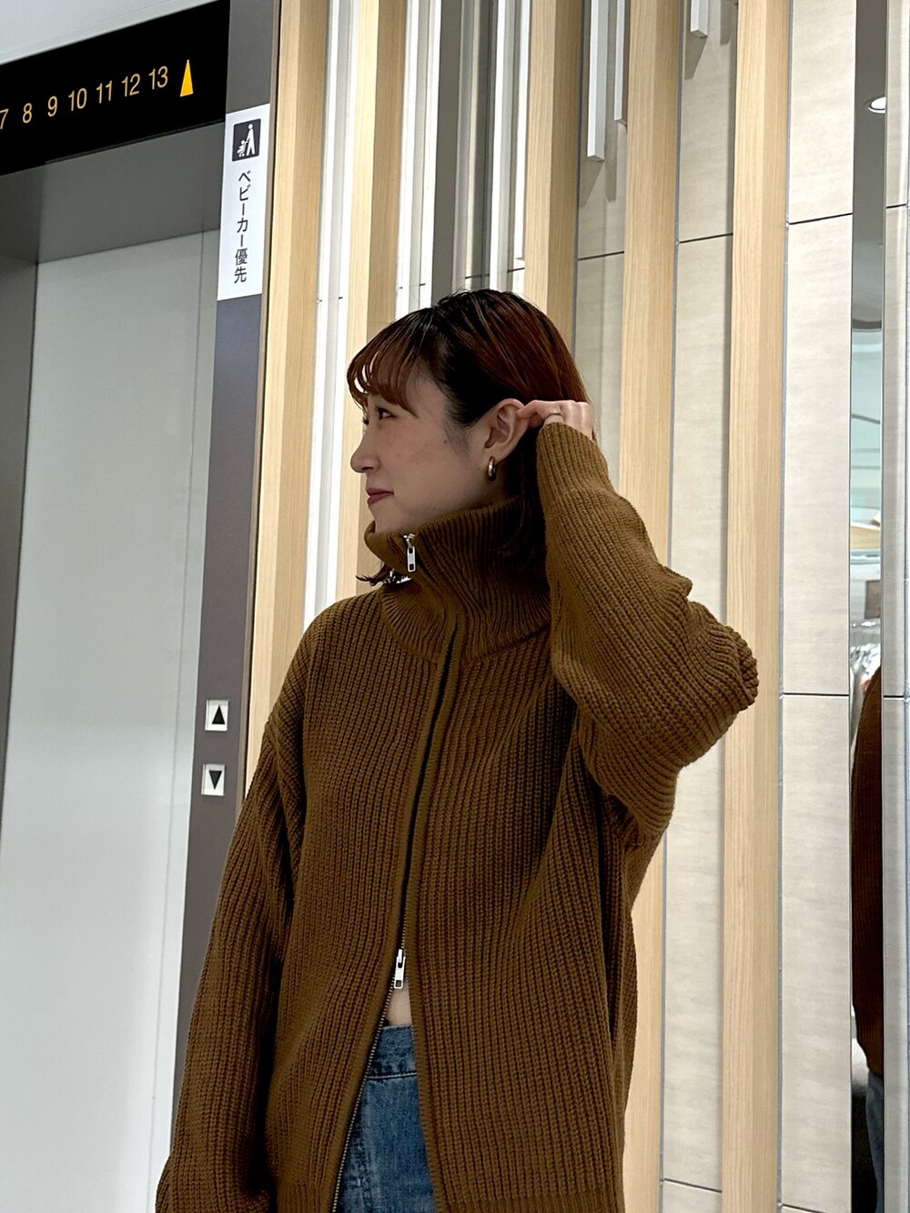 イエロー系のカーディガン/ボレロ、ブラック系のブーツ、ブルー系のデニムパンツを着用したレディースの秋コーディネートの4枚目の写真