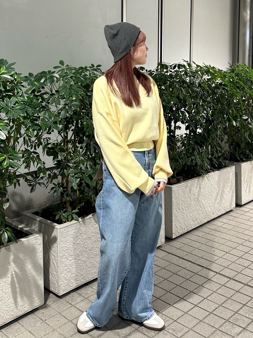 イエロー系のニット/セーター、ブルー系のデニムパンツ、グレー系のニットキャップ/ビーニーを着用したレディースの冬コーディネートの6枚目の写真