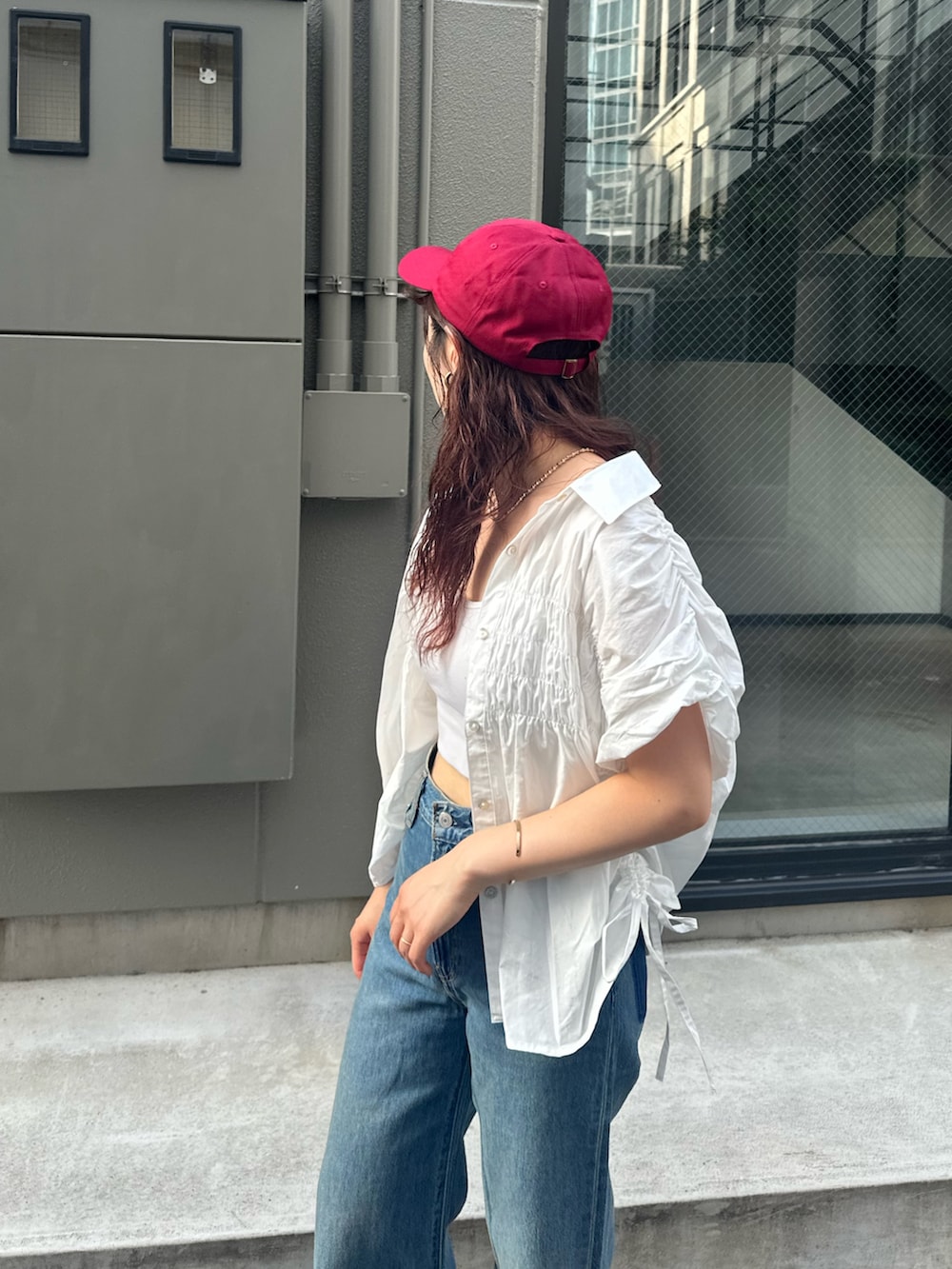 ブルー系のデニムパンツ、レッド系のキャップを着用したレディースの夏コーディネートの7枚目の写真