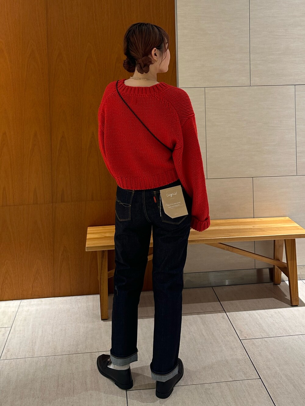 レッド系のカーディガン/ボレロ、ブルー系のデニムパンツ、ブラック系のショルダーバッグを着用したレディースの秋コーディネートの4枚目の写真