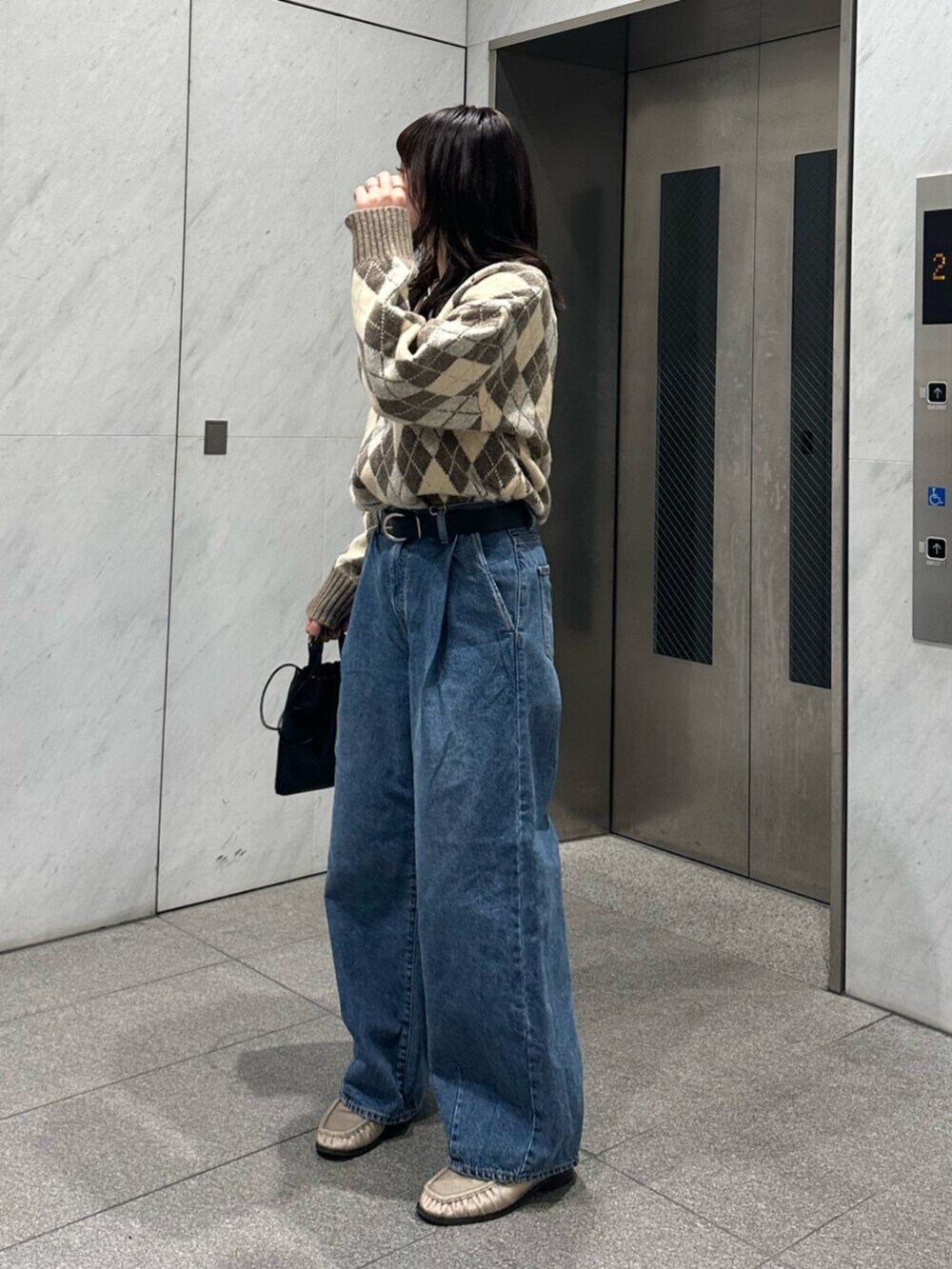 ベージュ系のニット/セーター、ブルー系のデニムパンツを着用したレディースの秋コーディネートの3枚目の写真