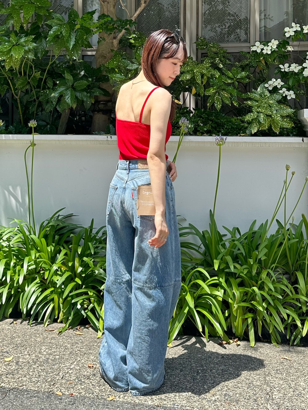 レッド系のキャミソール、ブルー系のデニムパンツを着用したレディースの夏コーディネートの5枚目の写真