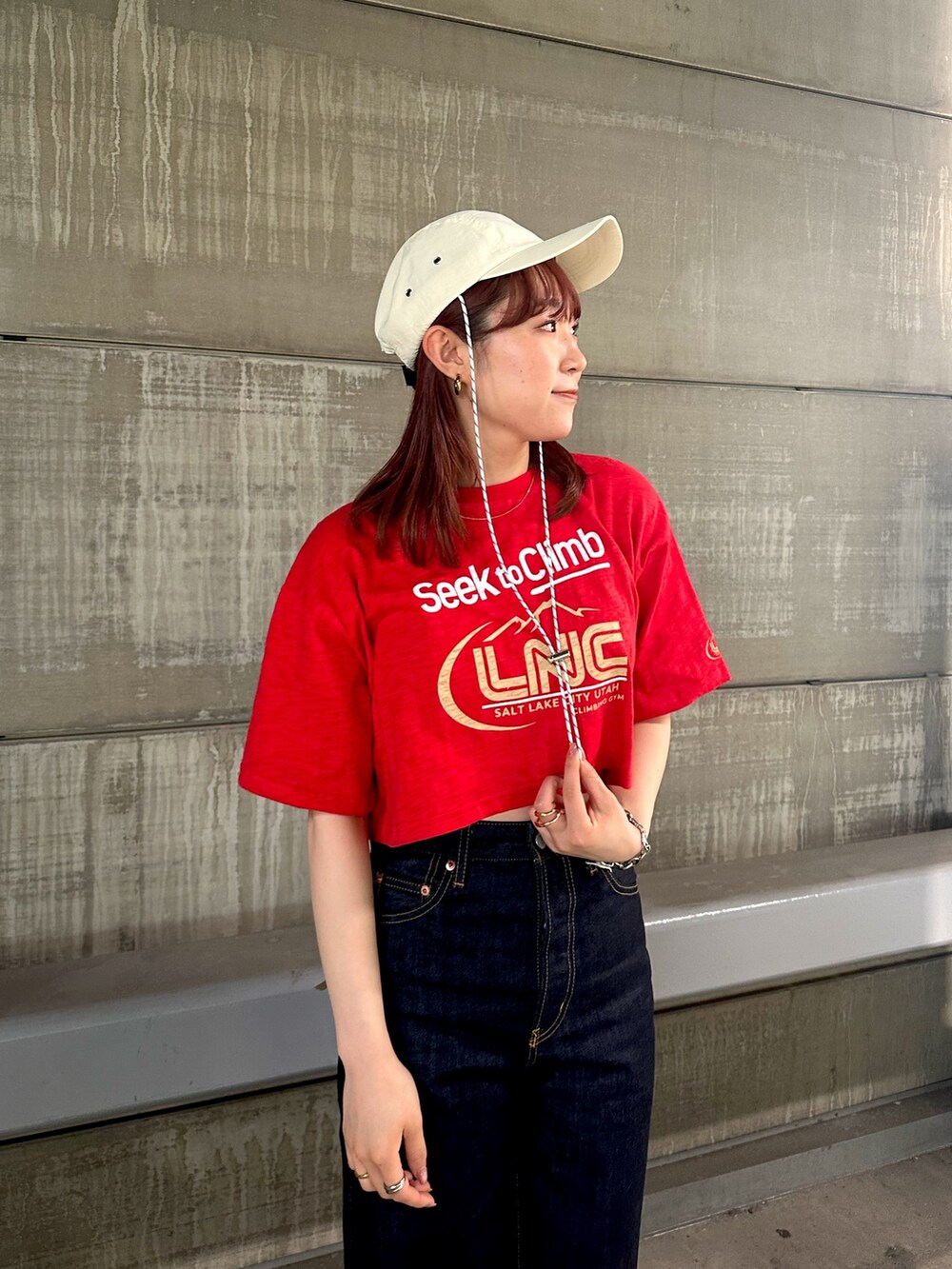 レッド系のTシャツ/カットソー、ブルー系のデニムパンツ、ホワイト系のキャップを着用したレディースの春コーディネートの6枚目の写真