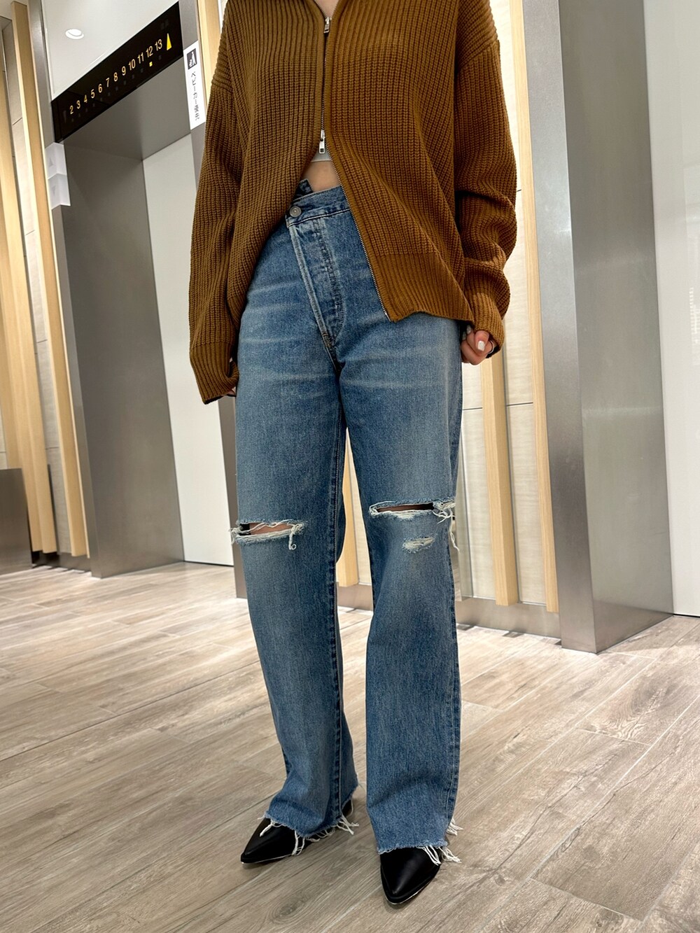 イエロー系のカーディガン/ボレロ、ブラック系のブーツ、ブルー系のデニムパンツを着用したレディースの秋コーディネートの5枚目の写真