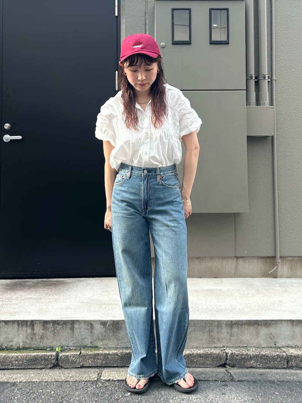 ブルー系のデニムパンツ、レッド系のキャップを着用したレディースの夏コーディネートの2枚目の写真