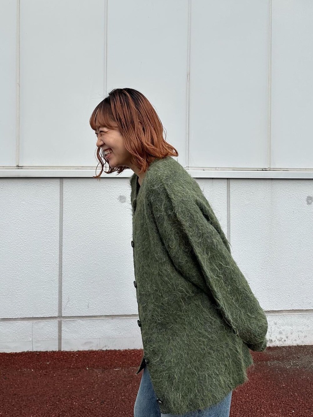 グリーン系のカーディガン/ボレロ、ブルー系のデニムパンツ、ブラック系のブーツを着用したレディースの秋コーディネートの4枚目の写真