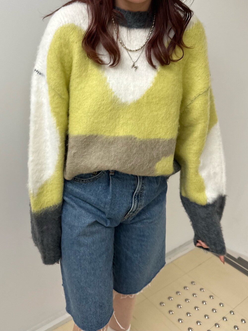 グリーン系のニット/セーター、ブルー系のデニムパンツを着用したレディースの秋コーディネートの5枚目の写真