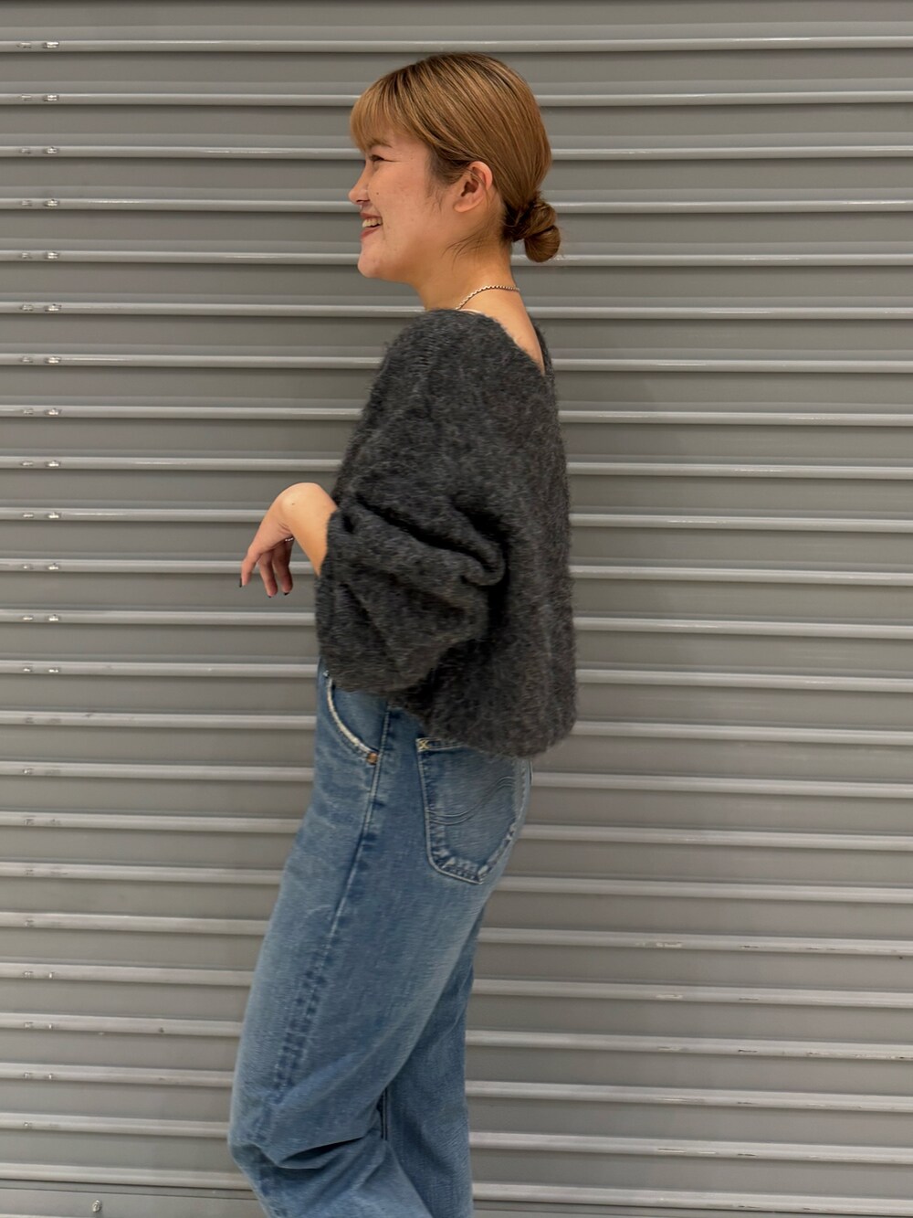 グレー系のニット/セーター、ブルー系のデニムパンツを着用したレディースの秋コーディネートの5枚目の写真