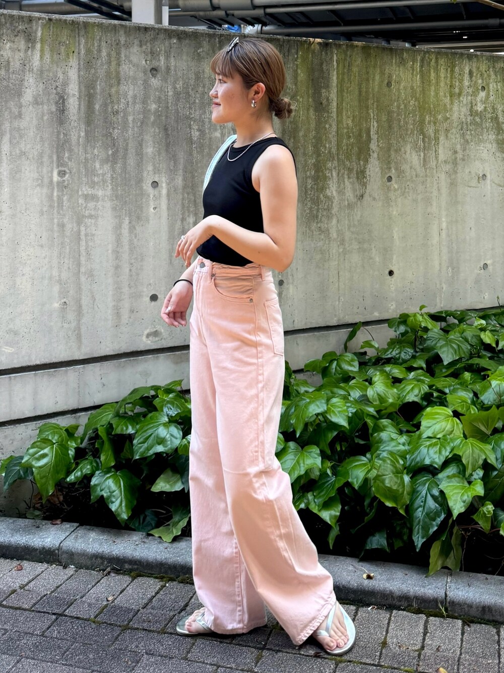 ブラック系のタンクトップ、ピンク系のデニムパンツ、シルバー系のハンドバッグを着用したレディースの春コーディネートの3枚目の写真