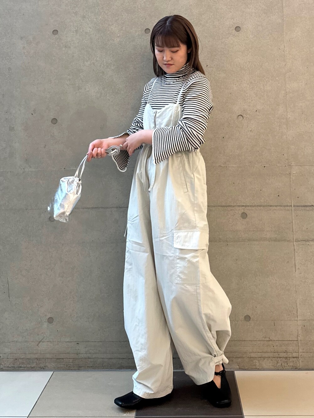 ホワイト系のニット/セーター、グレー系のサロペット/オーバーオール、ブラック系のパンプスを着用したレディースの冬コーディネートの2枚目の写真