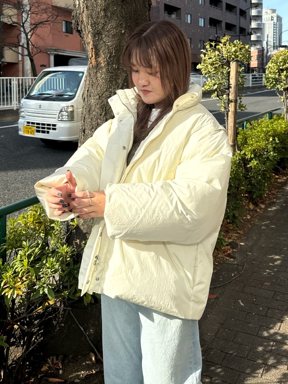 ブルー系のデニムパンツ、ホワイト系のダウンジャケット/コート、ベージュ系のニット/セーターを着用したレディースの冬コーディネートの6枚目の写真