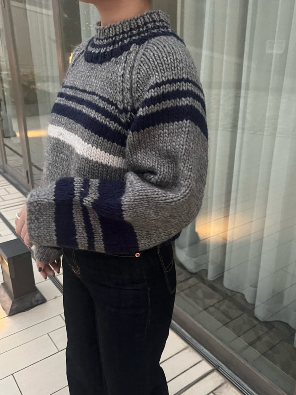 グレー系のニット/セーター、ブルー系のデニムパンツを着用したレディースの冬コーディネートの4枚目の写真
