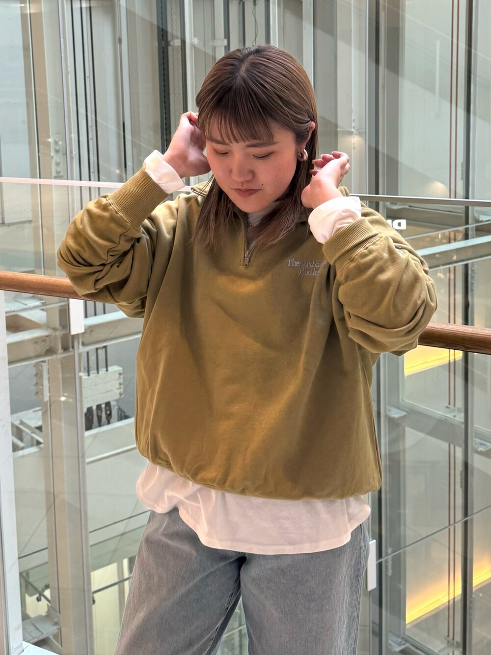 グリーン系のスウェット、ホワイト系のTシャツ/カットソー、ブルー系のデニムパンツを着用したレディースの冬コーディネートの3枚目の写真