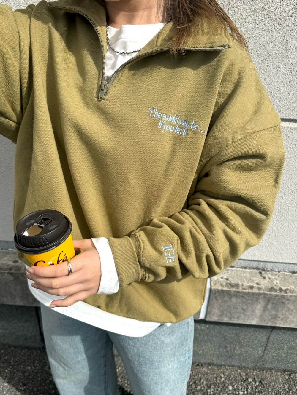 グリーン系のスウェット、ホワイト系のTシャツ/カットソー、ブルー系のデニムパンツを着用したレディースの冬コーディネートの4枚目の写真