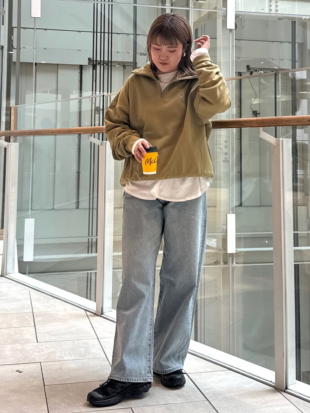 グリーン系のスウェット、ホワイト系のTシャツ/カットソー、ブルー系のデニムパンツを着用したレディースの冬コーディネートの2枚目の写真