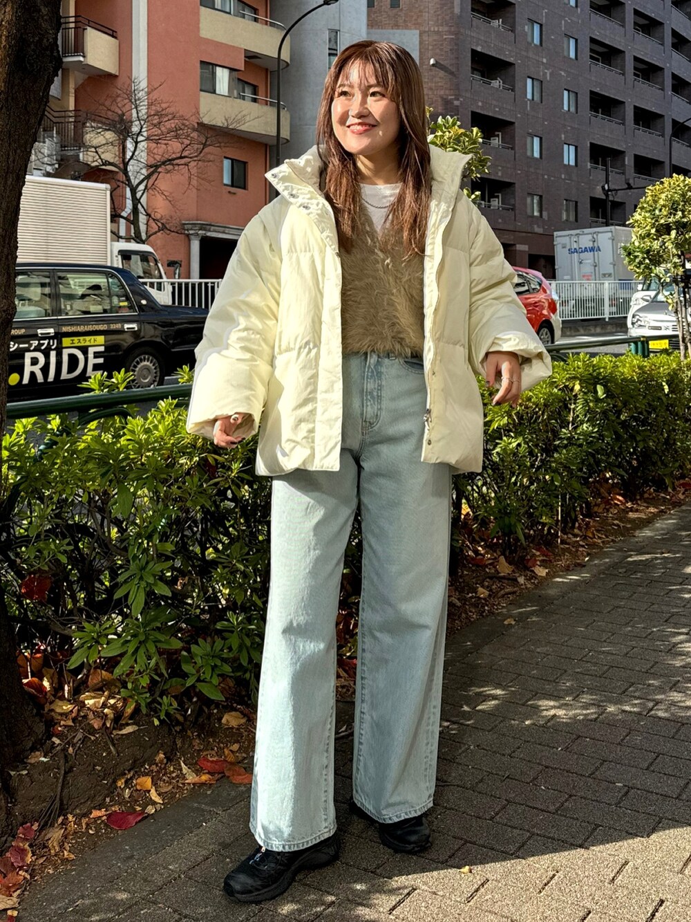 ブルー系のデニムパンツ、ホワイト系のダウンジャケット/コート、ベージュ系のニット/セーターを着用したレディースの冬コーディネートの2枚目の写真