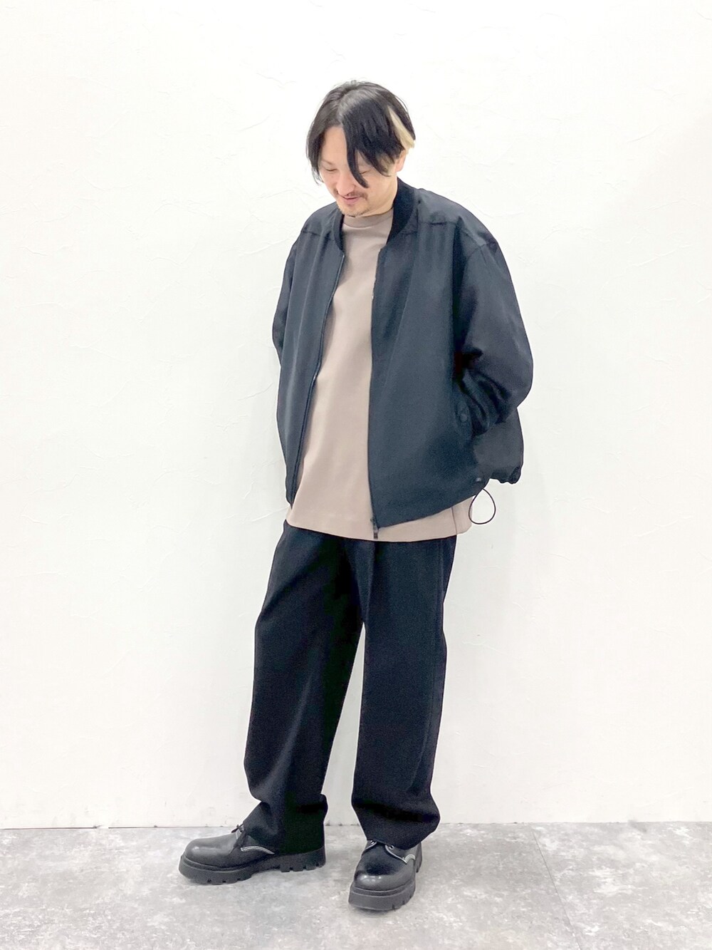 ブラック系のMA-1、ブラウン系のTシャツ/カットソー、ブラック系のスラックスを着用したメンズの春コーディネートの3枚目の写真
